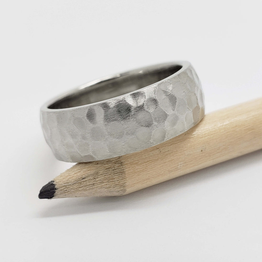 14kt white gold hammered wedding band displayed on a pencil