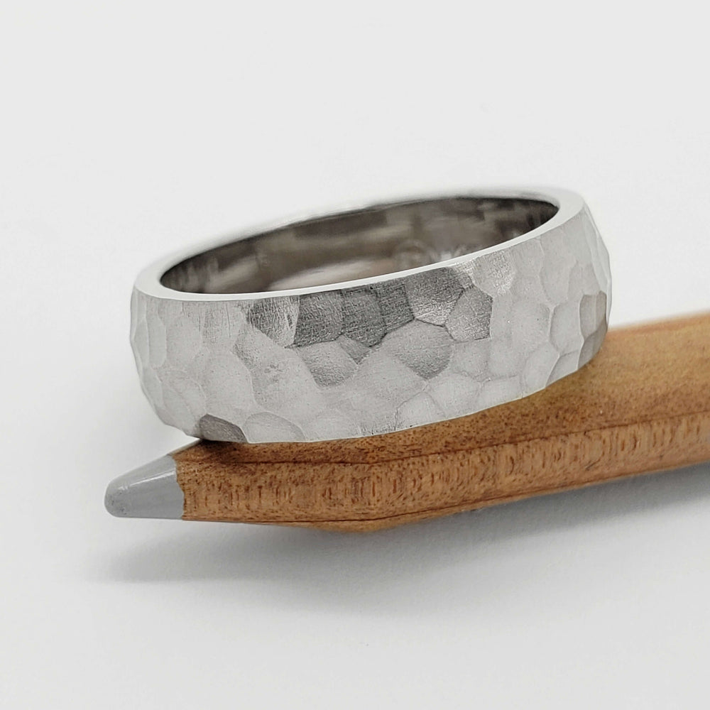 14kt white gold hammered wedding ring displayed on a wooden pencil