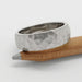 14kt white gold hammered wedding ring displayed on a wooden pencil