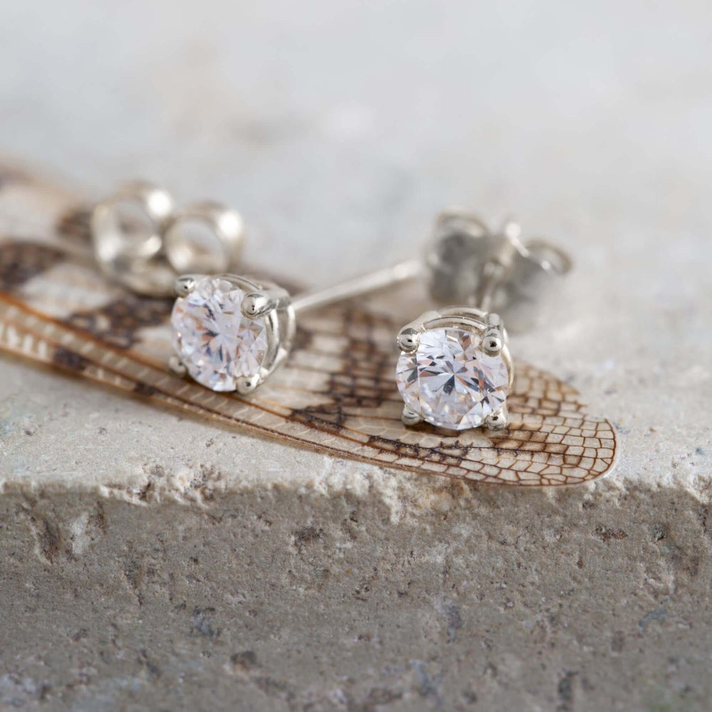 Close-up of 14kt white gold lab diamond stud earrings on a textured surface