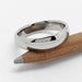 14kt white gold low dome wedding band resting on a wooden pencil
