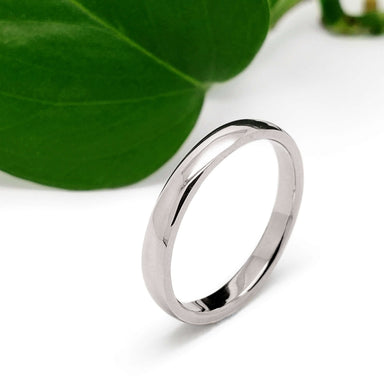 14kt white gold low dome wedding ring with high polish finish beside a green leaf