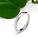 14kt white gold low dome wedding ring with high polish finish beside a green leaf