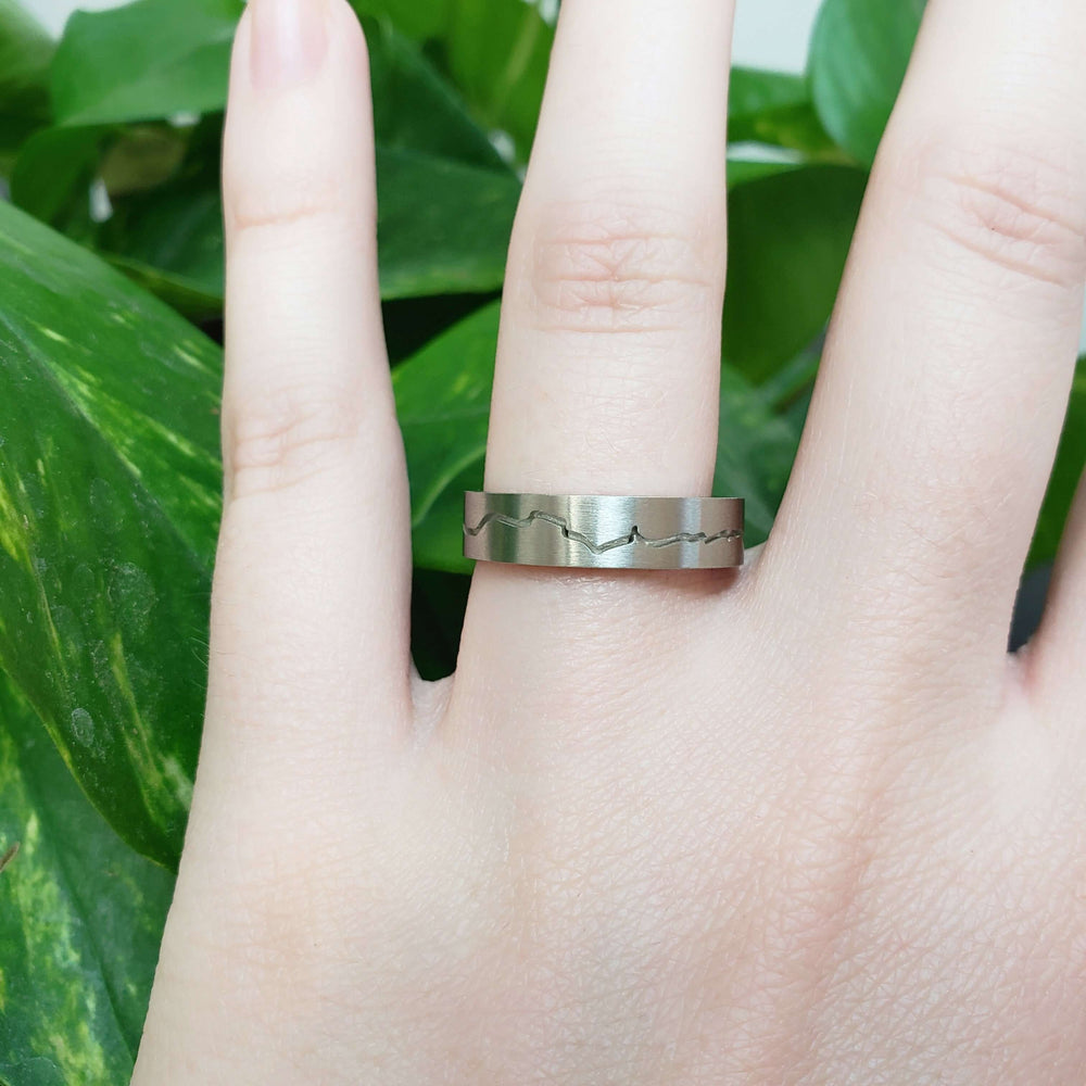 14kt white gold mountain range wedding ring worn on hand, brushed finish