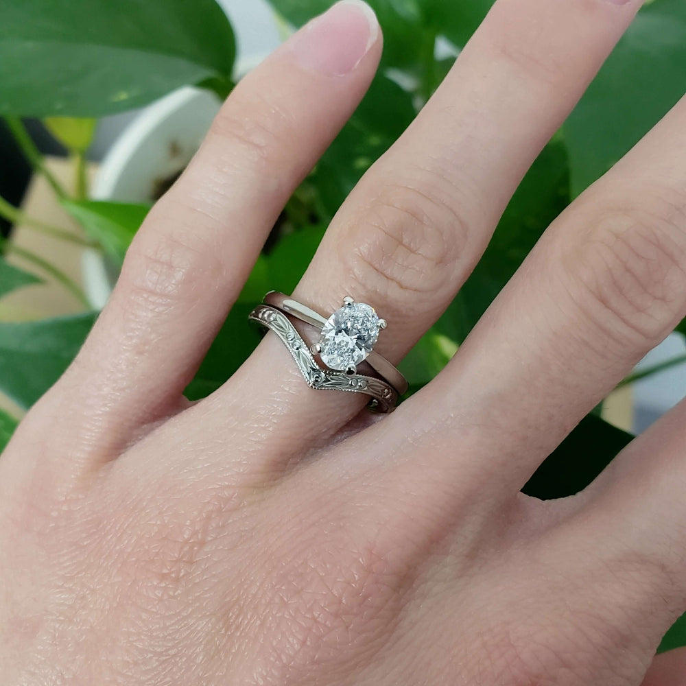 14kt white gold oval lab diamond engagement ring paired with engraved wedding band on hand