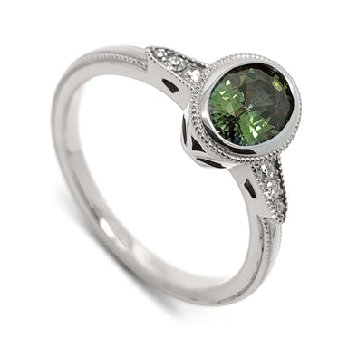 14kt white gold ring with oval green Australian sapphire and Canadian diamonds, bezel-set with millgrain detail
