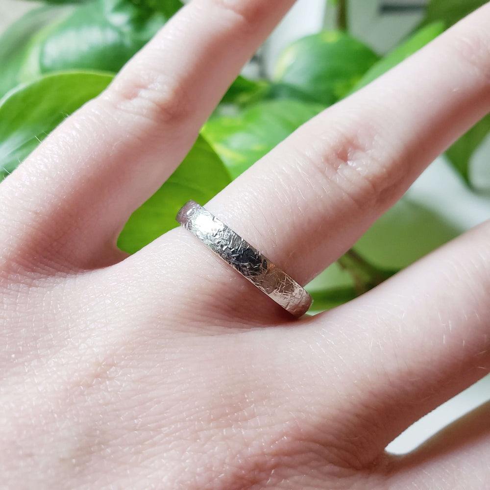 14kt white gold textured wedding band shown on a hand