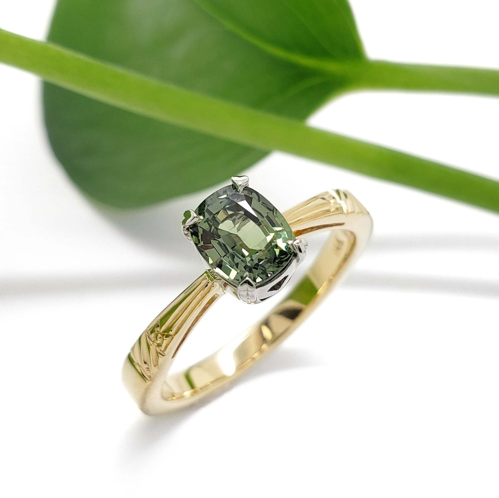 14kt yellow and white gold engagement ring with green sapphire, shown with leaf background