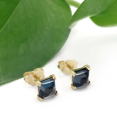 14kt yellow gold London blue topaz stud earrings with green leaf background