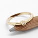 14kt yellow gold bezel set diamond ring displayed on a pencil