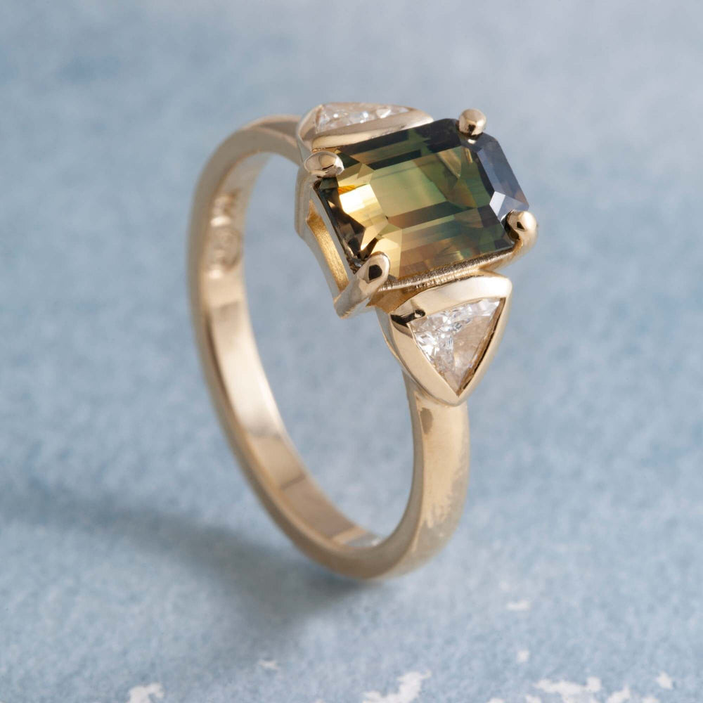 14kt yellow gold bi-coloured sapphire and trillion diamond ring on blue background
