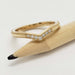 Close-up of 14kt yellow gold chevron diamond wedding ring resting on a pencil