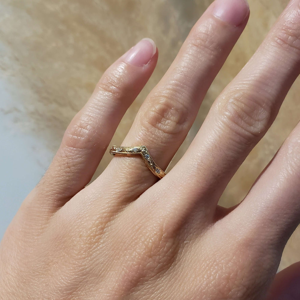 14kt yellow gold chevron diamond wedding ring shown on a hand
