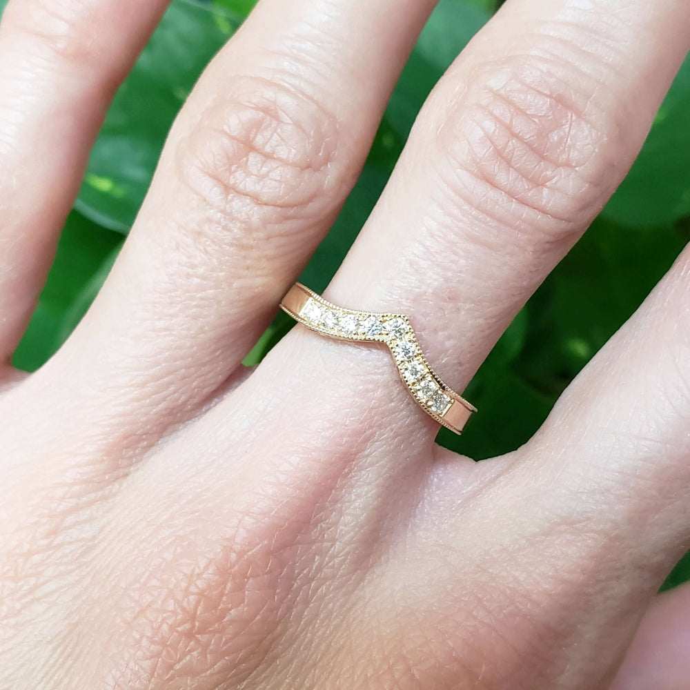 14kt yellow gold chevron diamond wedding ring with millgrain, shown on hand
