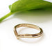 14kt yellow gold chevron wedding band with millgrain, shown beside a green leaf