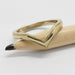 14kt yellow gold chevron wedding ring with millgrain resting on a pencil