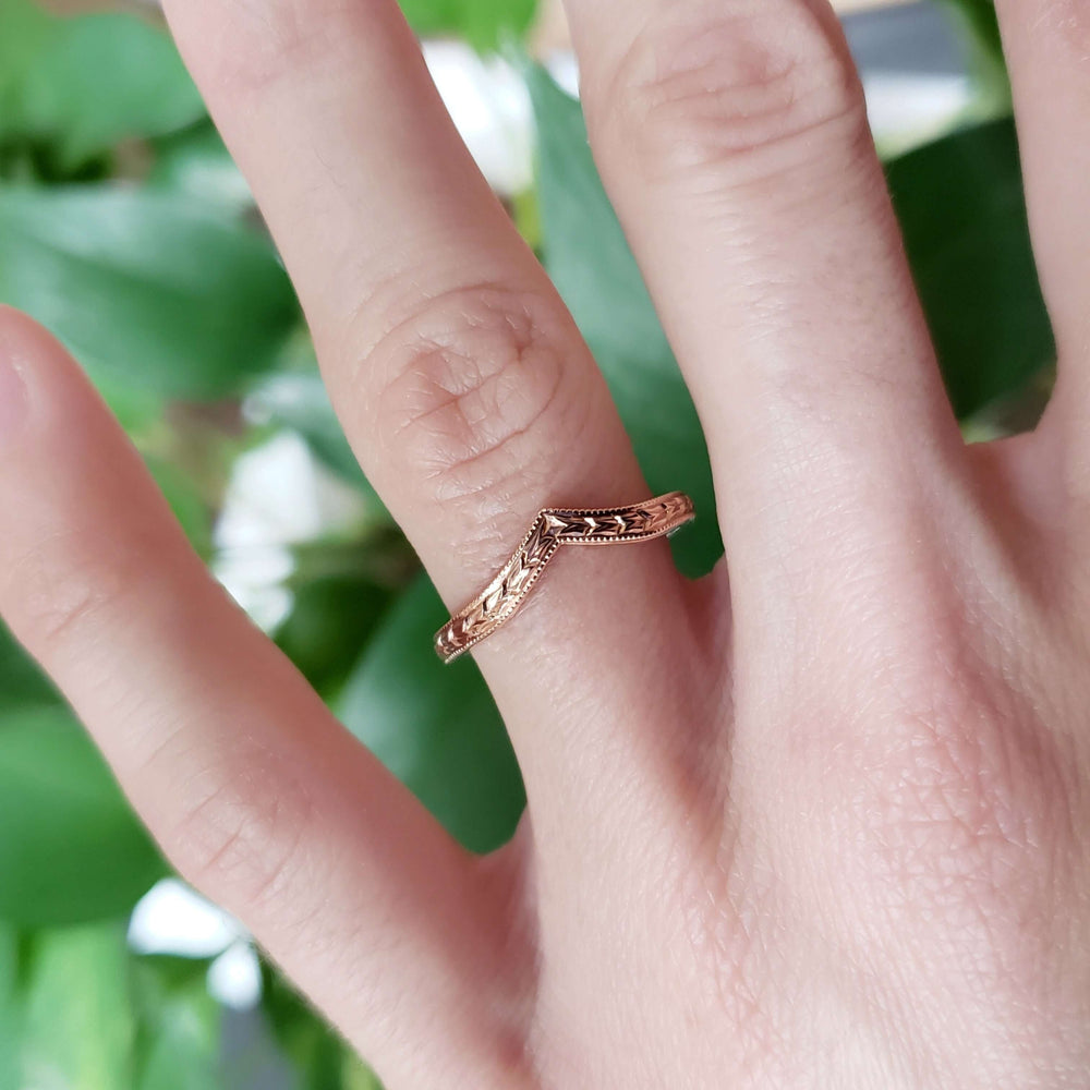 14kt yellow gold chevron wedding ring with wheat engraving, worn on a finger