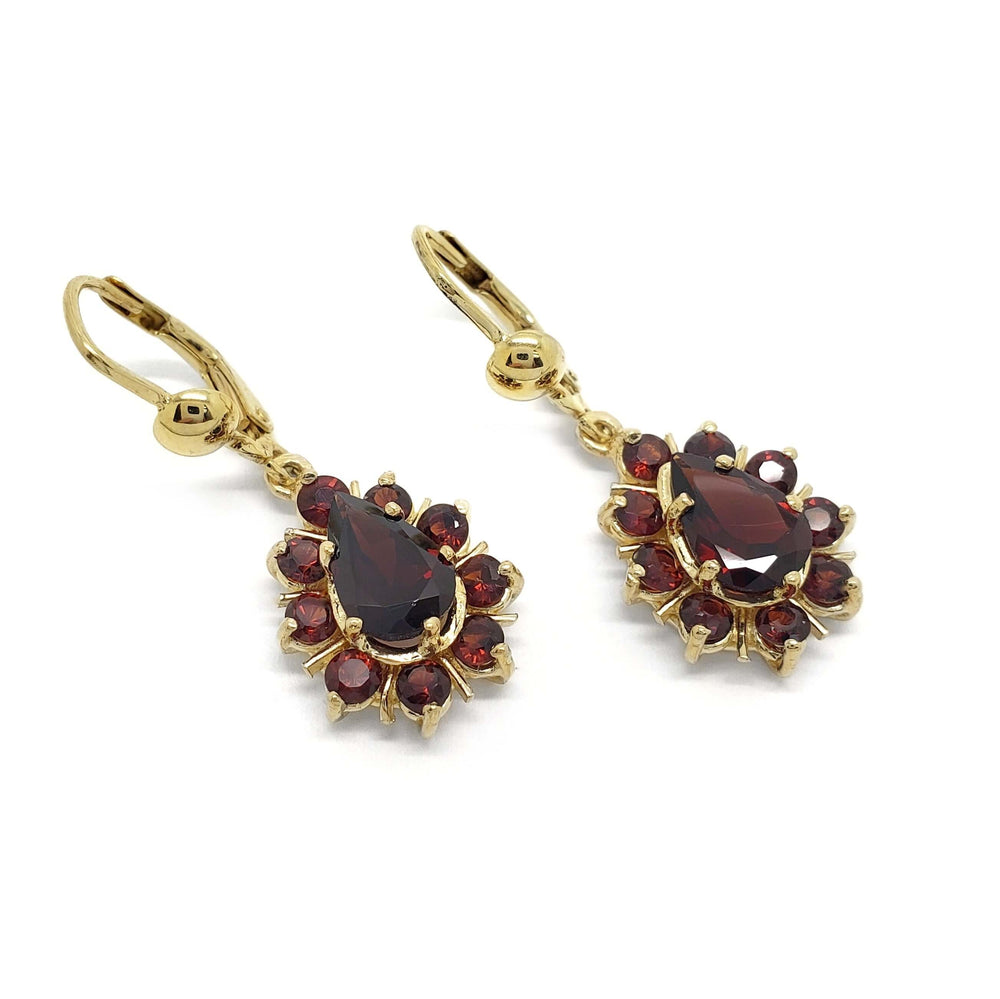 Pair of 14kt yellow gold dangle earrings with pear-shaped garnet centers and round garnet halos