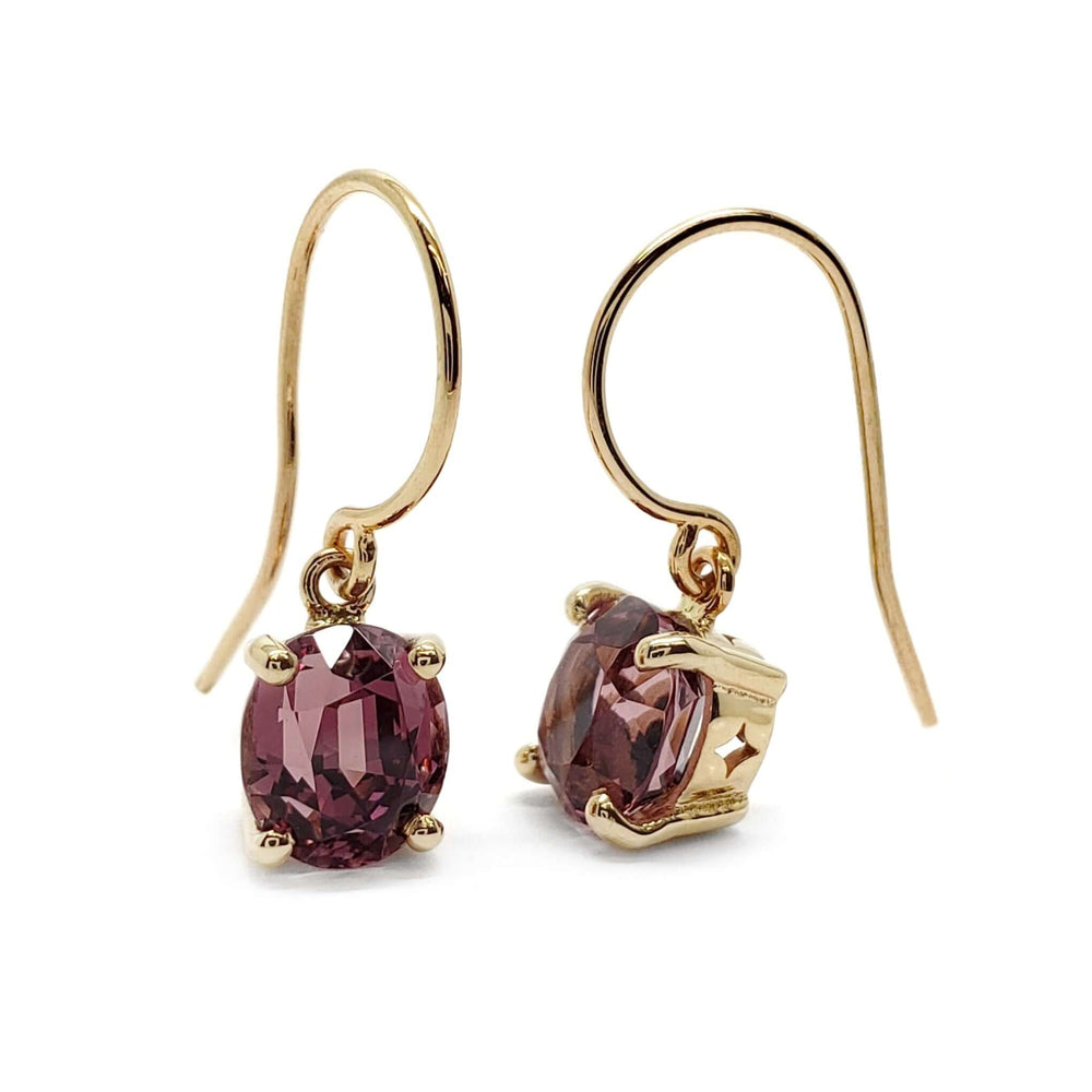 Pair of 14kt yellow gold drop earrings with oval Madagascar garnets on white background
