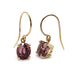 Pair of 14kt yellow gold drop earrings with oval Madagascar garnets on white background