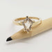 14kt yellow gold engagement ring with shield cut grey sapphire, shown on a pencil