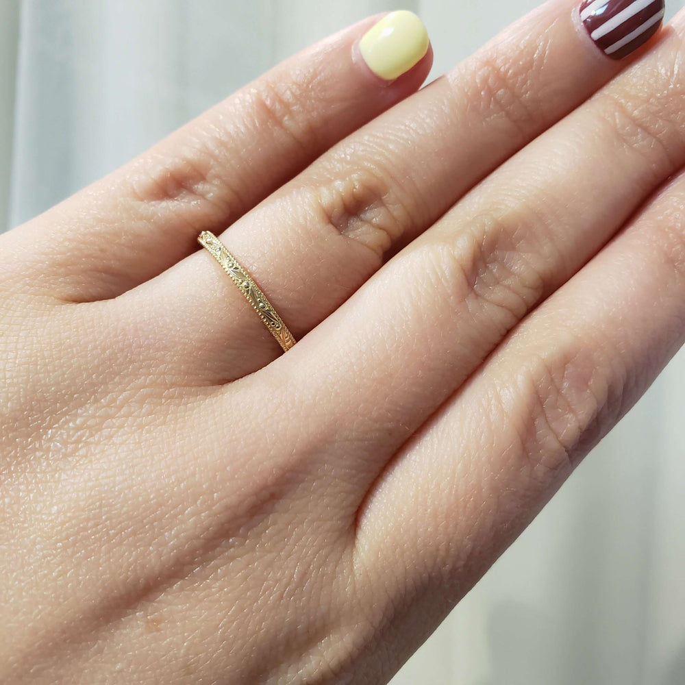 14kt yellow gold engraved wedding ring worn on a hand