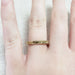 14kt yellow gold engraved wedding ring with millgrain edge shown on hand
