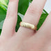 14kt yellow gold hammered wedding ring worn on a hand