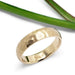 14kt yellow gold hammered wedding ring on white background with green leaf