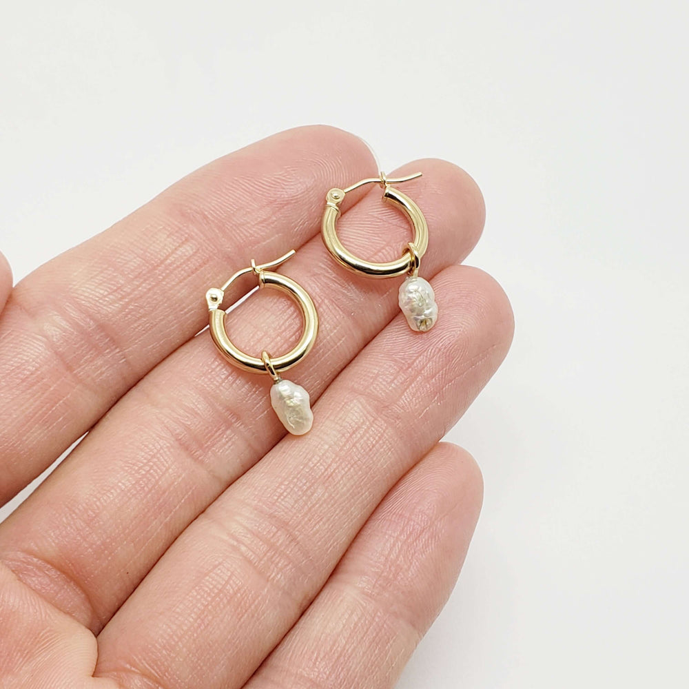 Hand holding 14kt yellow gold hoop earrings with detachable white vintage pearls