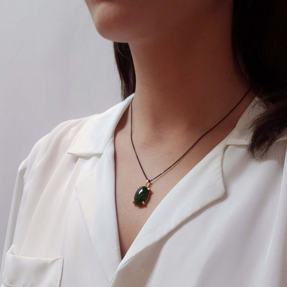 Model wearing 14kt yellow gold jade pendant on a dark chain