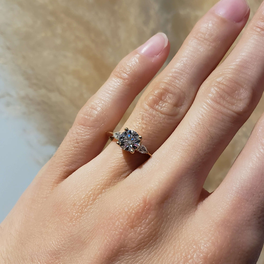 14kt yellow gold lab diamond engagement ring with pear accents shown on a hand