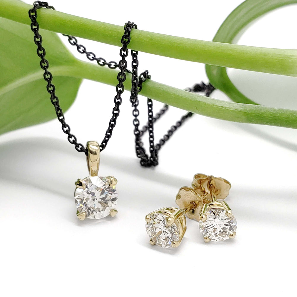 14kt yellow gold lab diamond stud earrings and matching pendant on black chain, displayed on a green stem