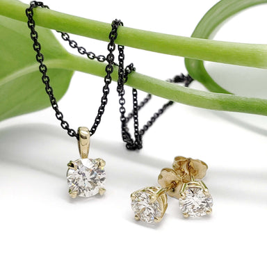14kt yellow gold lab diamond stud earrings and matching pendant on black chain, displayed on a green stem