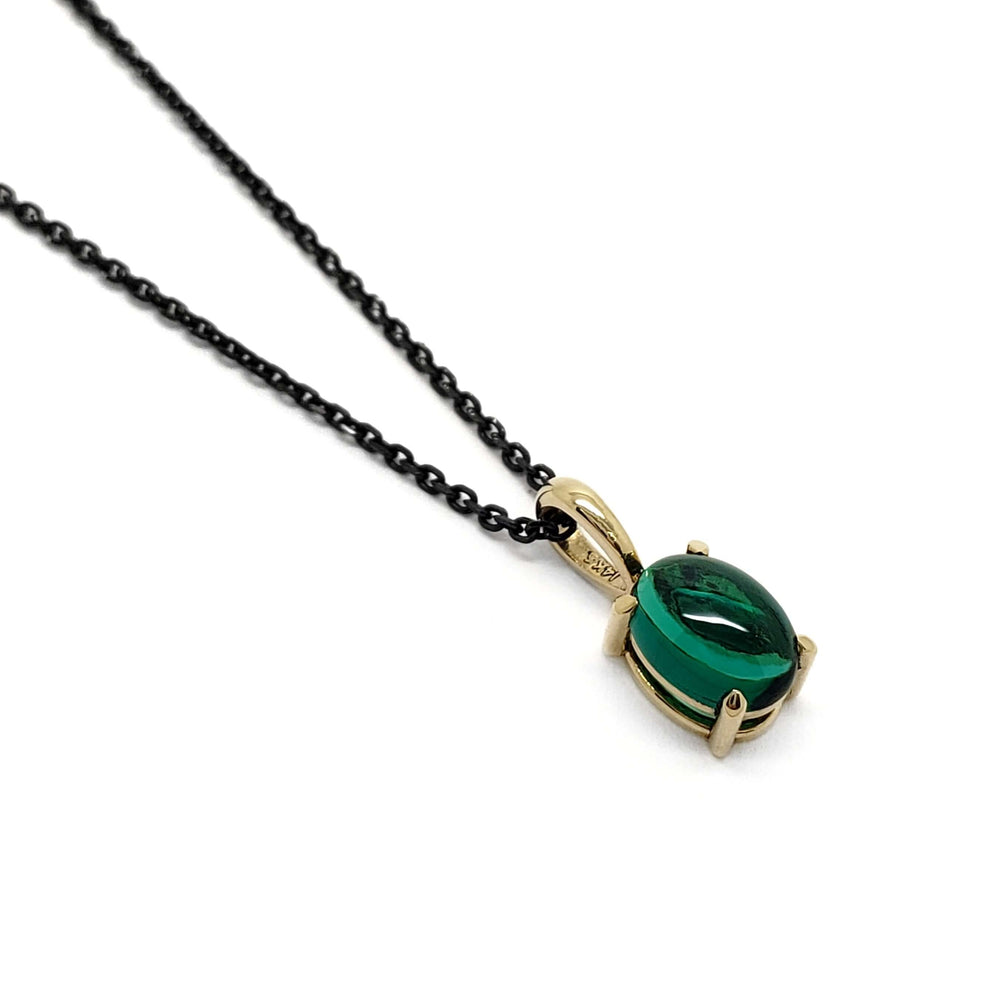14kt yellow gold pendant with oval cabochon lab emerald on a black chain, angled view