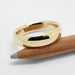 14kt yellow gold low dome wedding ring resting on a pencil