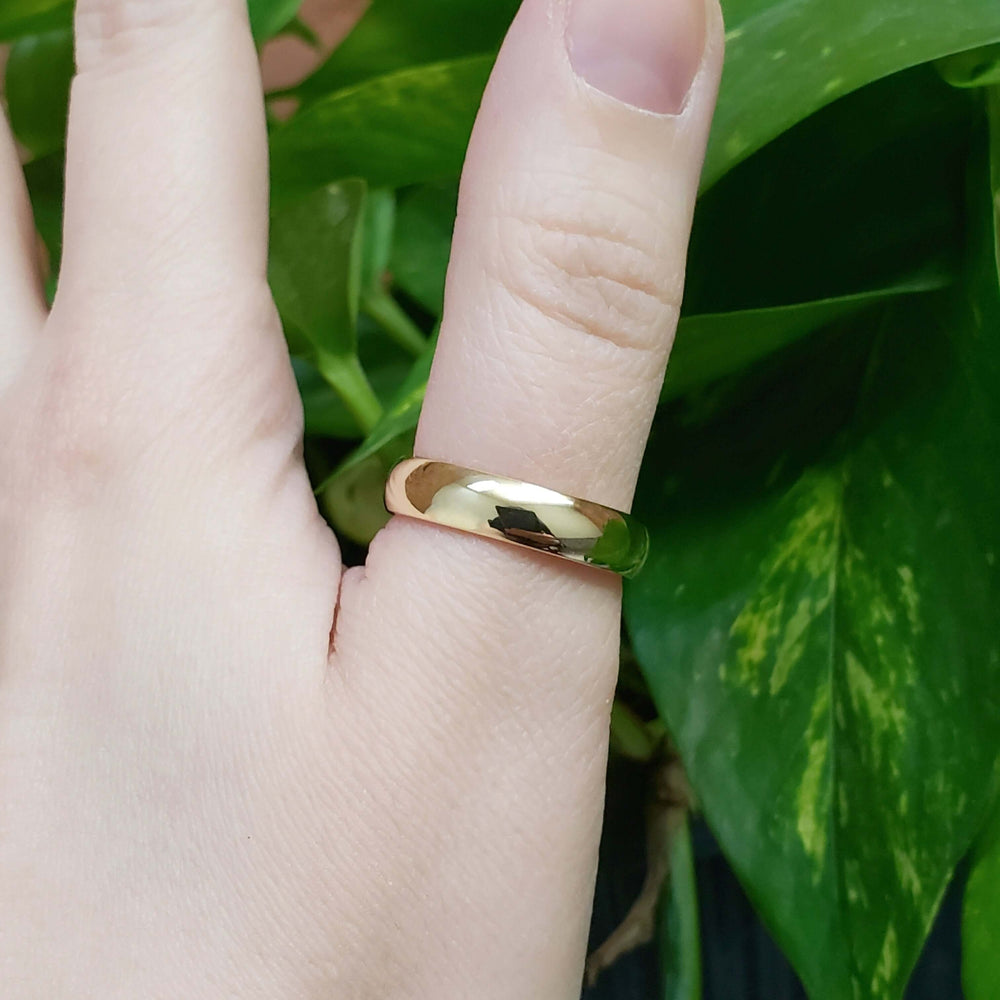 14kt yellow gold low dome wedding ring worn on a hand