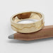 14kt yellow gold mountain range wedding ring resting on a pencil, showing textured band