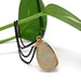 14kt yellow gold opal bezel pendant displayed with black chain and green leaf