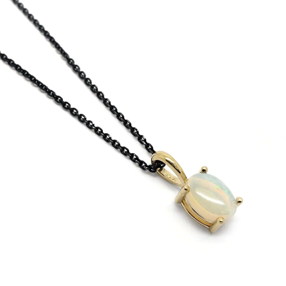 14kt yellow gold pendant with oval cabochon opal on black chain, angled on white background
