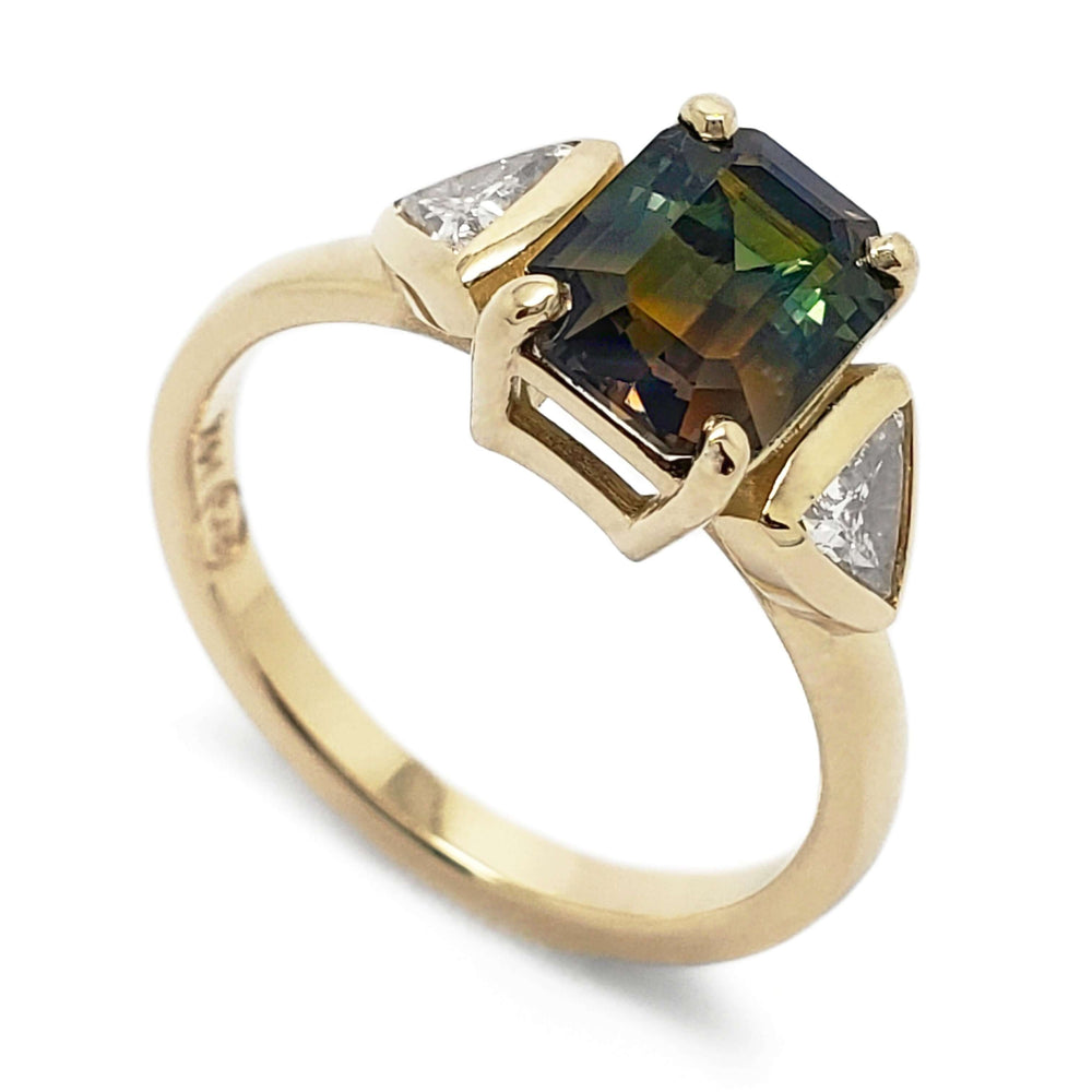 14kt yellow gold ring with emerald cut bi-coloured sapphire and trillion diamond side stones