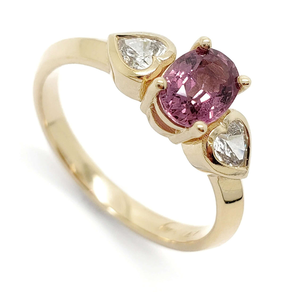14kt yellow gold ring with oval pink sapphire and two heart-shaped lab diamonds
