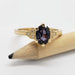 14kt yellow gold ring with oval purple sapphire and diamond details, displayed on pencil