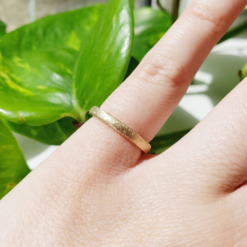 14kt yellow gold saw blade texture wedding band worn on a hand