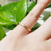 14kt yellow gold saw blade texture wedding band worn on a hand