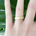 14kt yellow gold saw blade wedding band shown on a hand