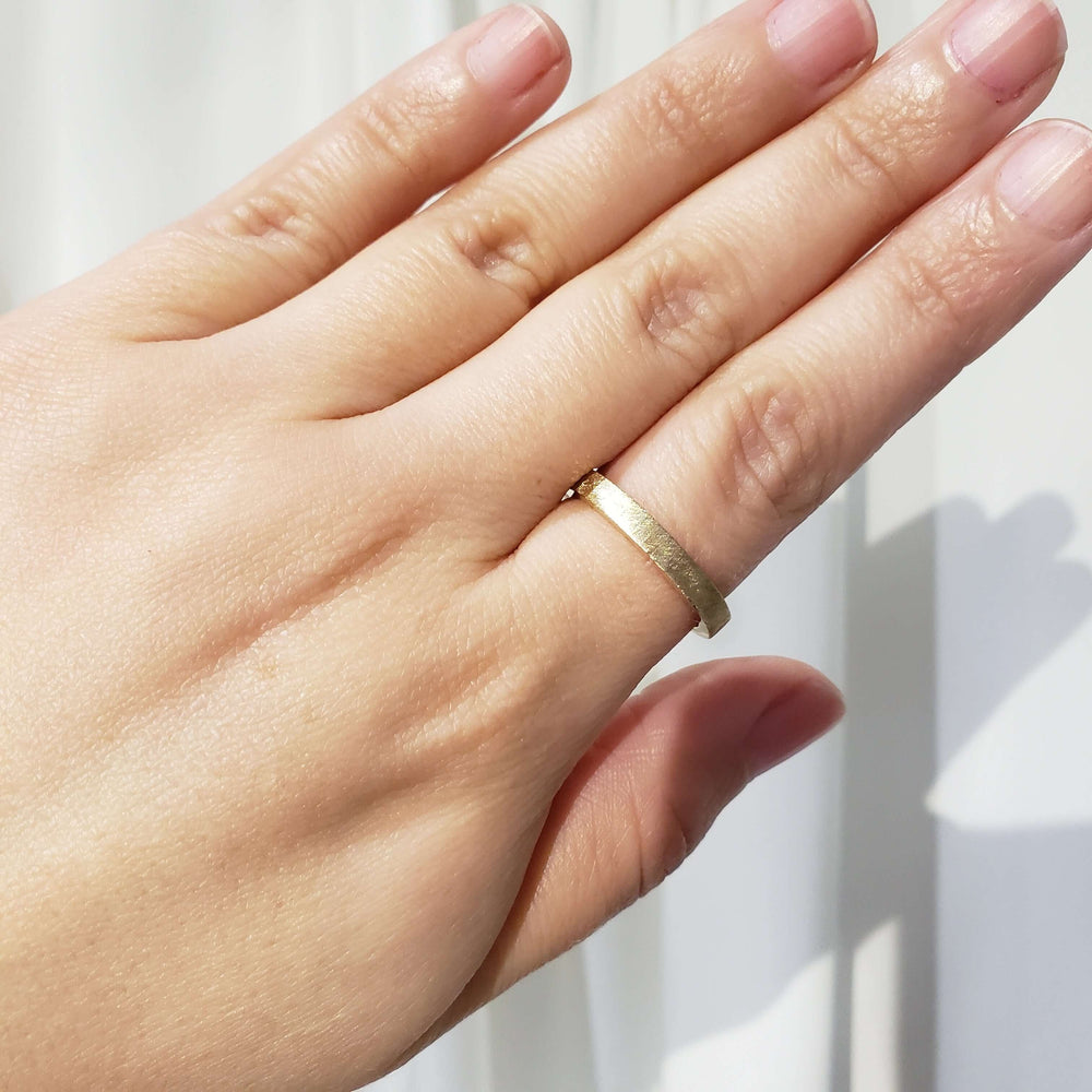 14kt yellow gold saw blade wedding ring worn on hand, showing brushed finish