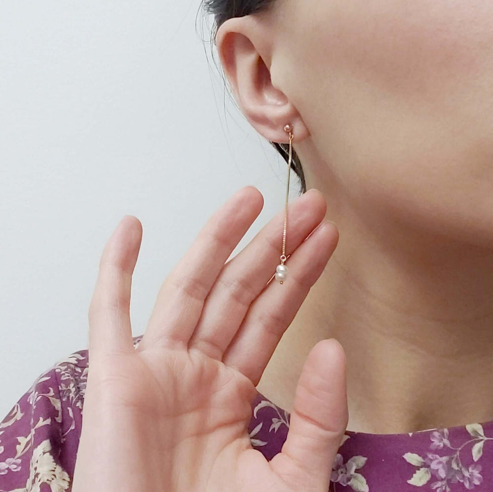 Model wearing a 14kt yellow gold dangle earring with seed pearls