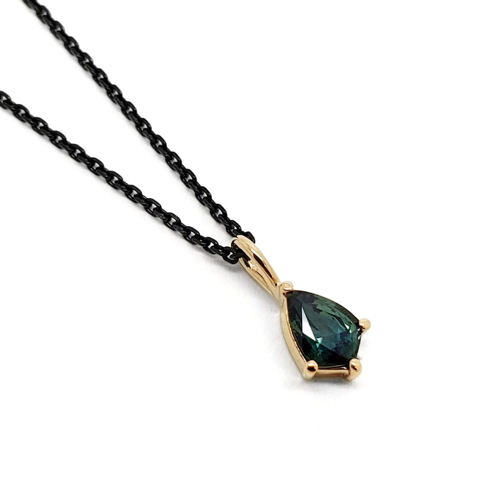 14kt yellow gold pendant with shield-cut green sapphire on a black chain, white background