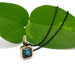 14kt yellow gold teal tourmaline bezel pendant on black chain, styled with green leaves